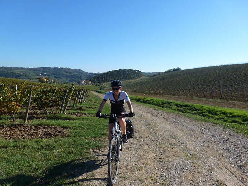 Femme à vélo sur chemin de terre entre vignes