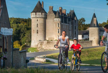 Parents et leur garçon à vélo devant le château de Montpoupon