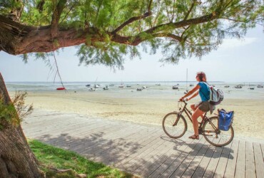 Femme à vélo qui roule à vélo le long de la plage