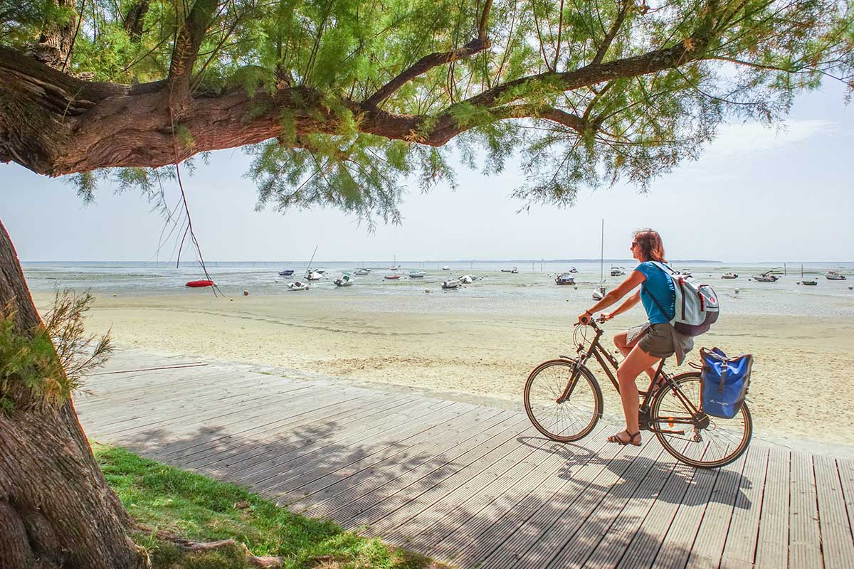 Femme à vélo qui roule à vélo le long de la plage