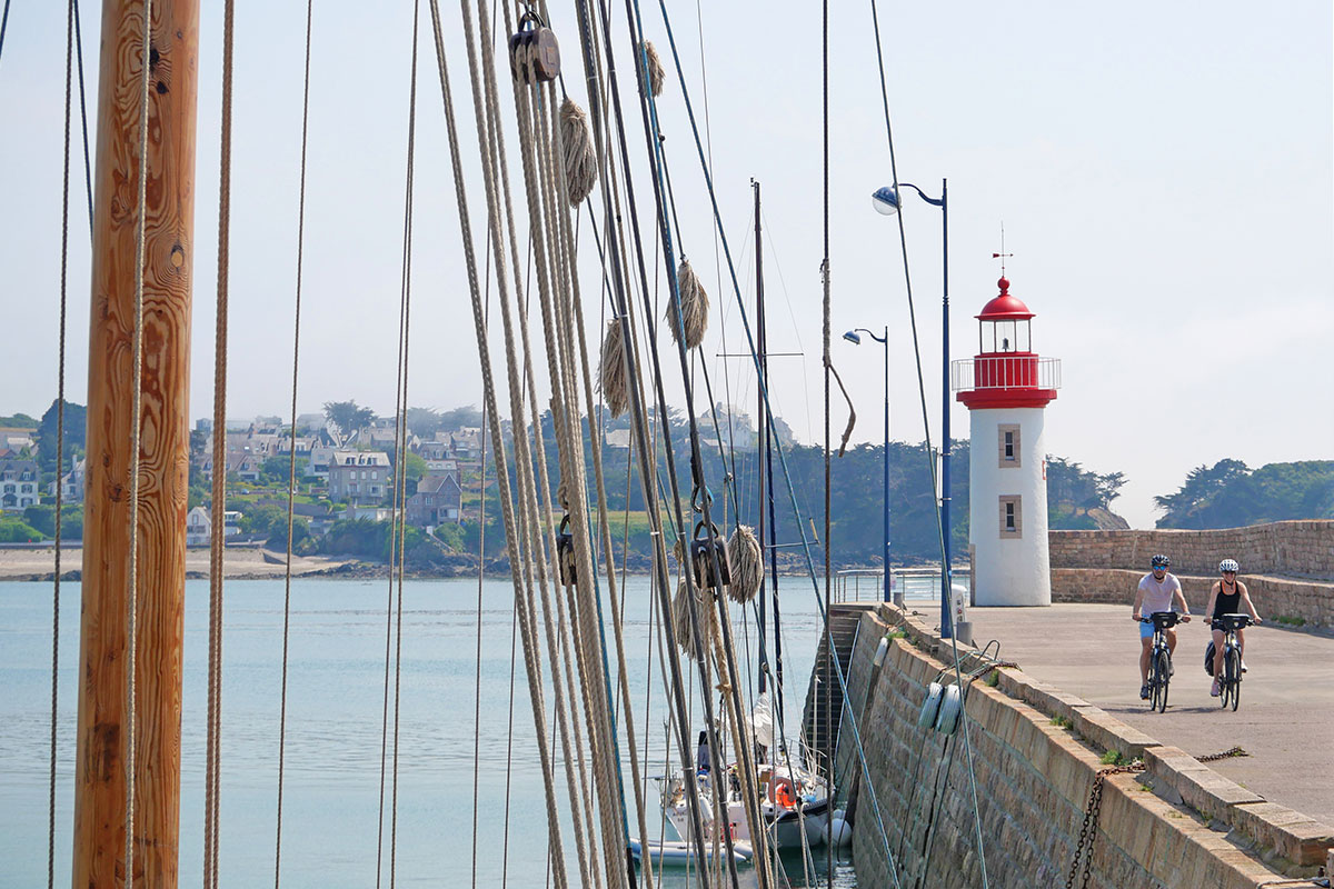 Deux cycliste longeant un port sur la route d'un phare breton