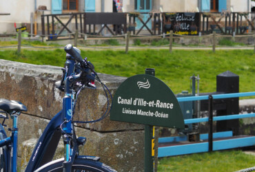 Un vélo électrique posé contre le muret d'un pont d'une écluse