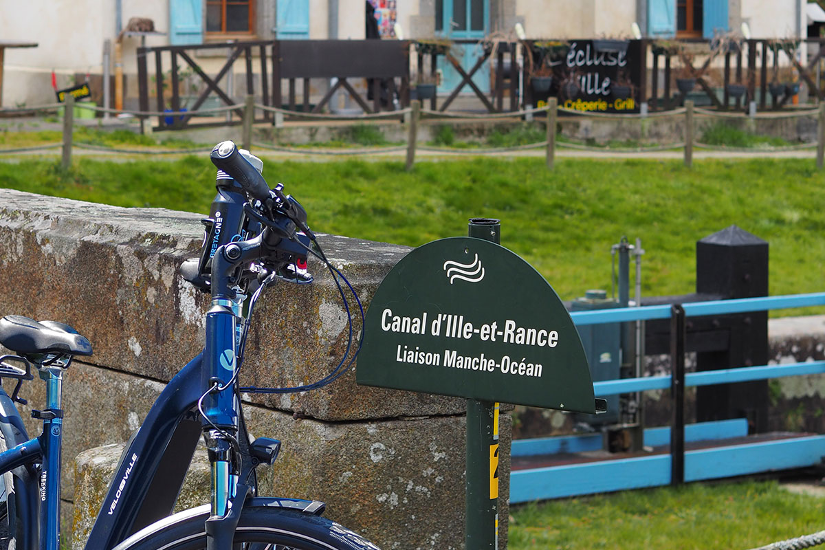 Un vélo électrique posé contre le muret d'un pont d'une écluse 