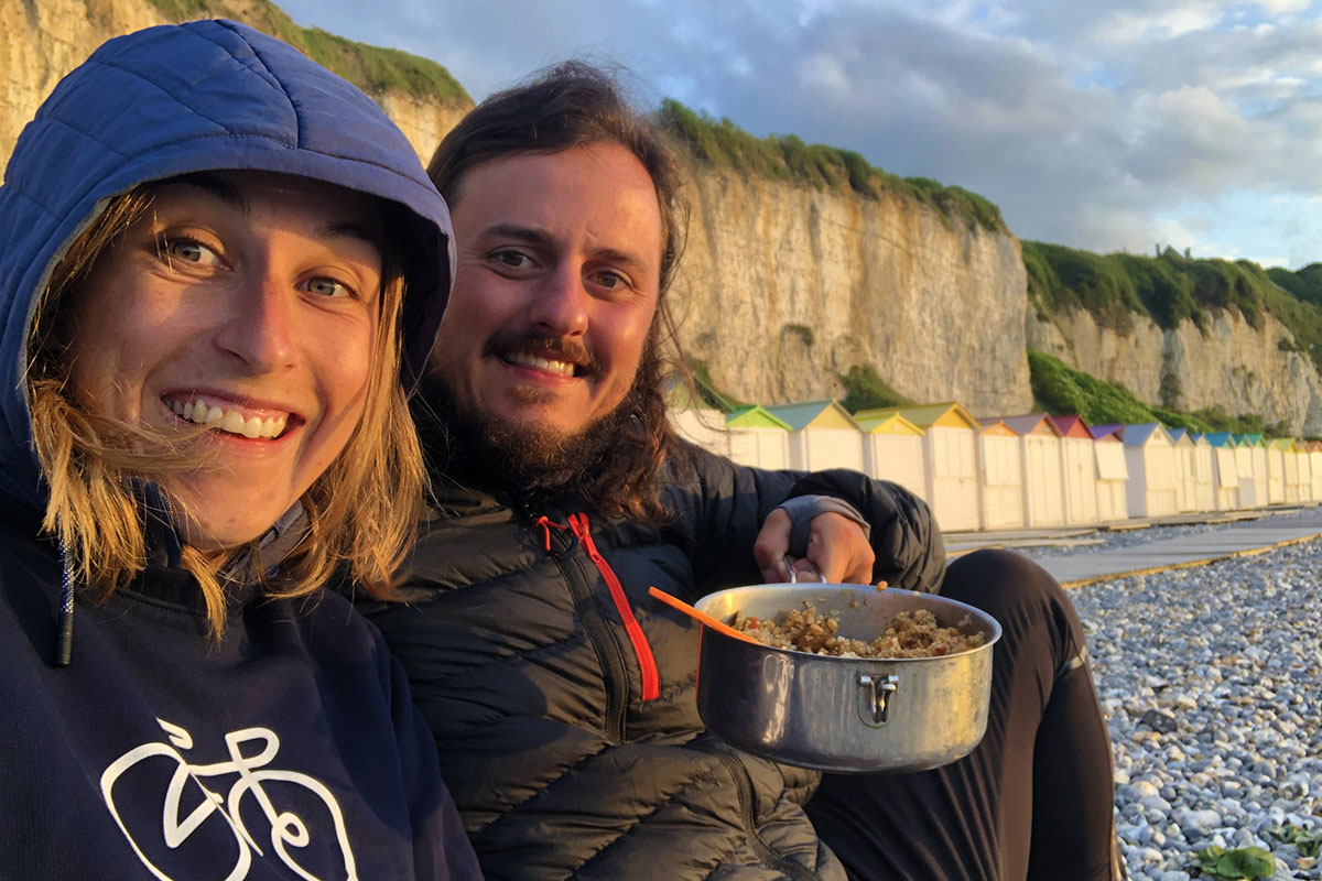 Constant et Julie sur une plage de galets devant leur repas du soir.