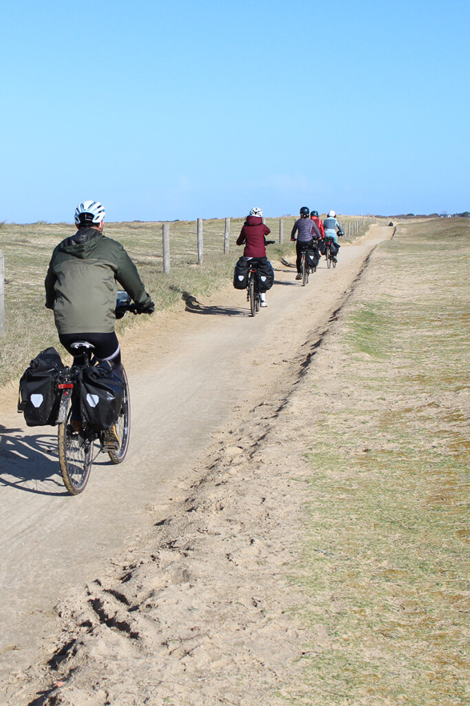 A group of cyclists ride along the dunes on the Brittany coast