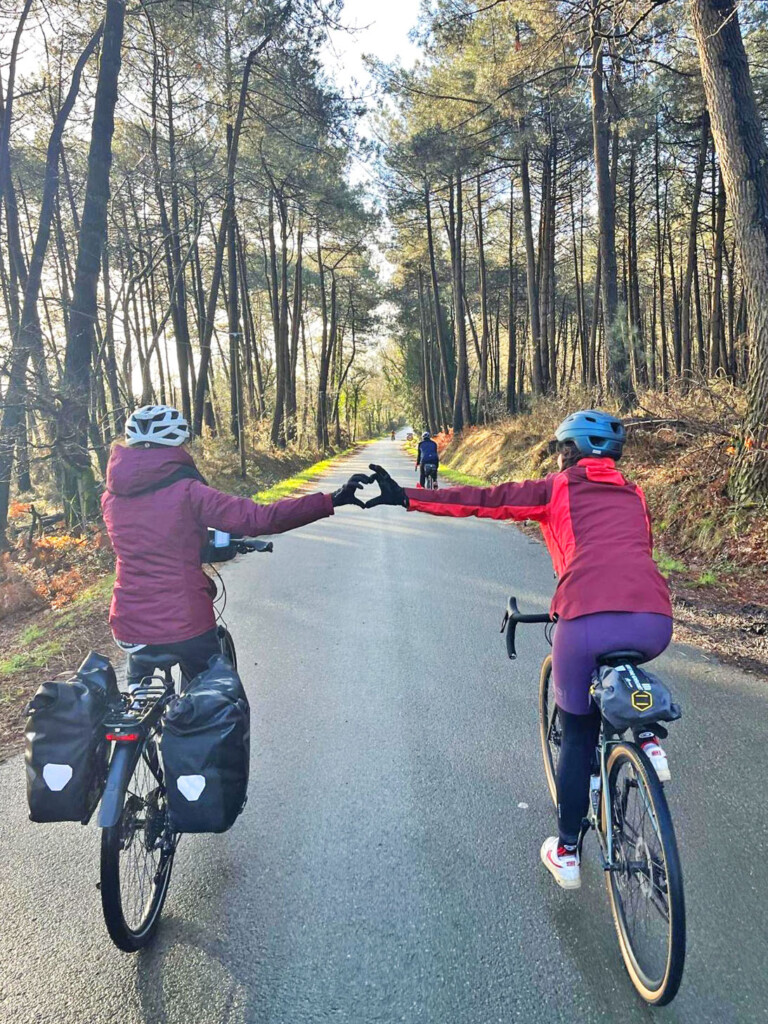 Deux cyclistes de dos roulants sur une piste cyclable entourée de forêt