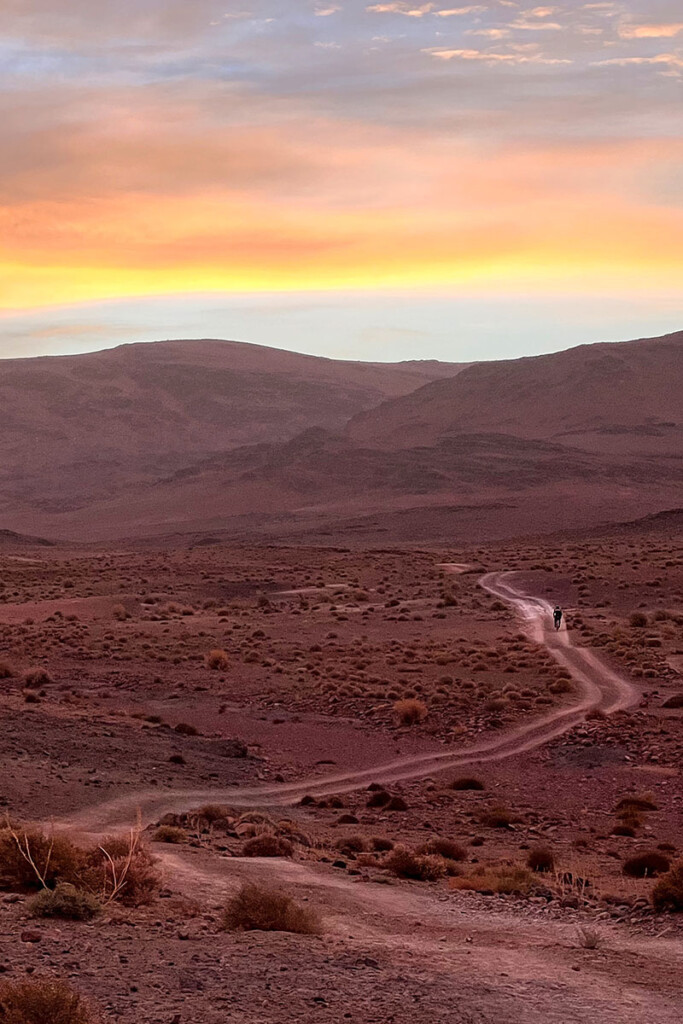Lever de soleil aux couleurs de feu sur une piste rouge du désert marocain