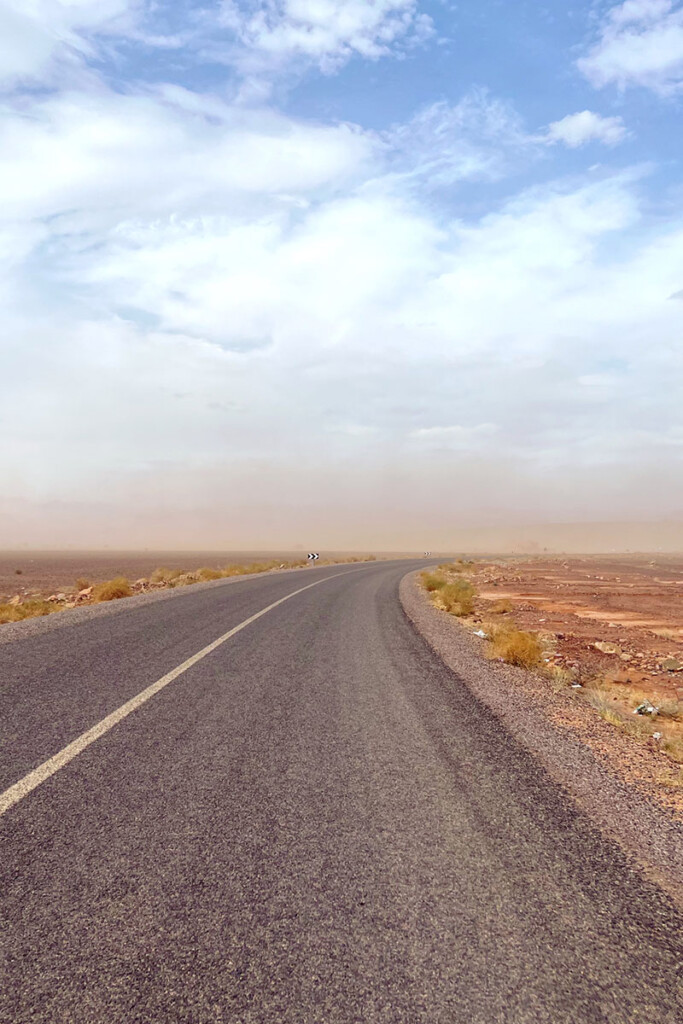 Tempête de sable taversant une route goudronnée au milieu du desert