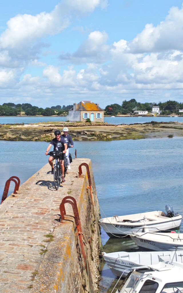 Deux cyclistes sur une digue pavée le long de la mer