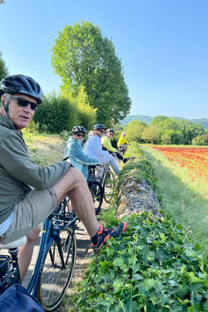 Un groupe de cycliste pose devant un champ de coquelicots