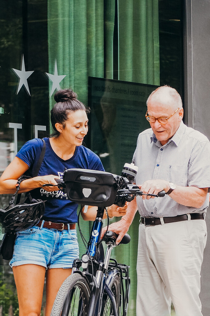 Une Agent d'Accueil Abicyclette Voyages montre le vélo de location à un monsieur