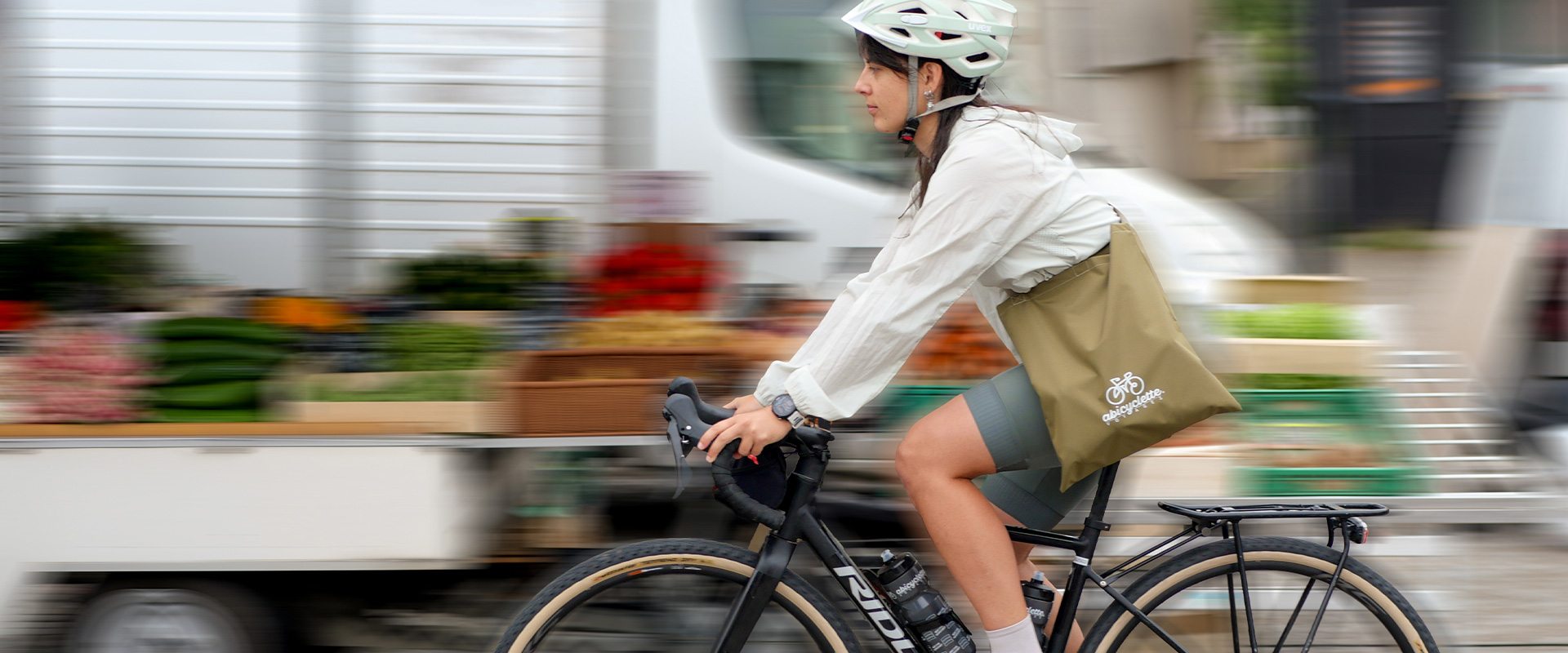 Une cycliste porte en bandoulière un sac kaki abicyclette voyages