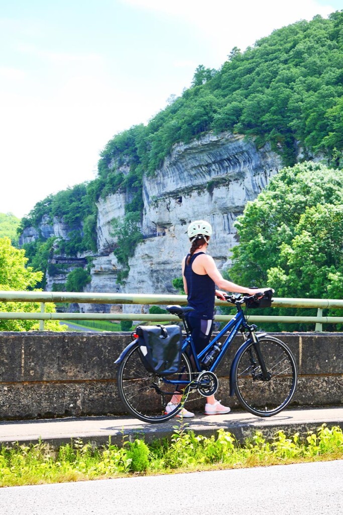 Une cycliste marche aux cotes de son velo de voyage