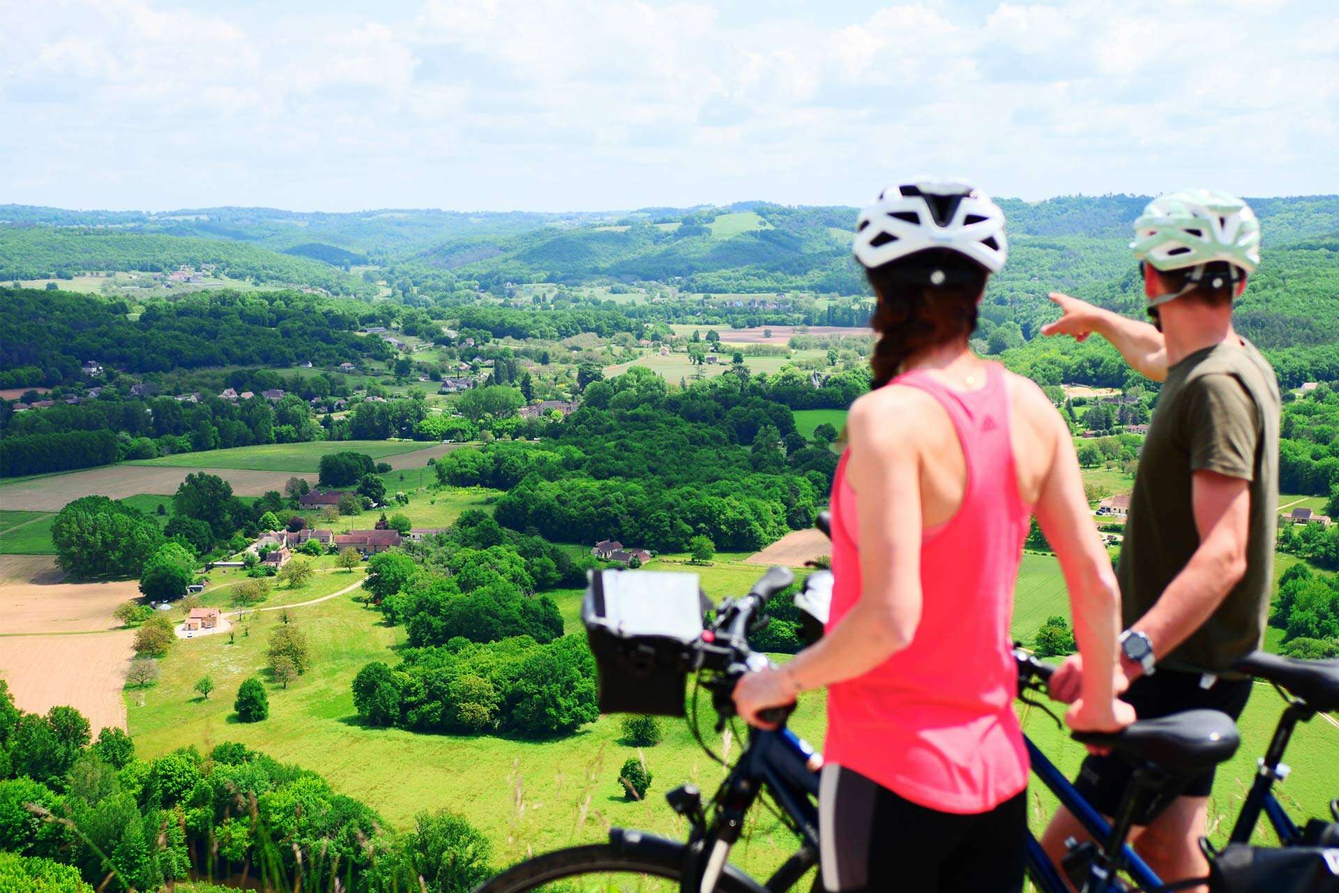 A couple of cyclists in front of a panorama of landscapes