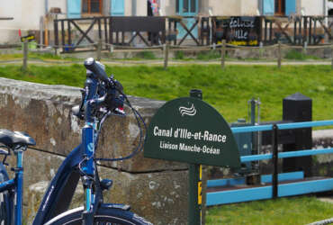 An electric bike rests against the low wall of a lock bridge