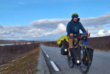 Valentin is on his bike on a road through a Nordic landscape.