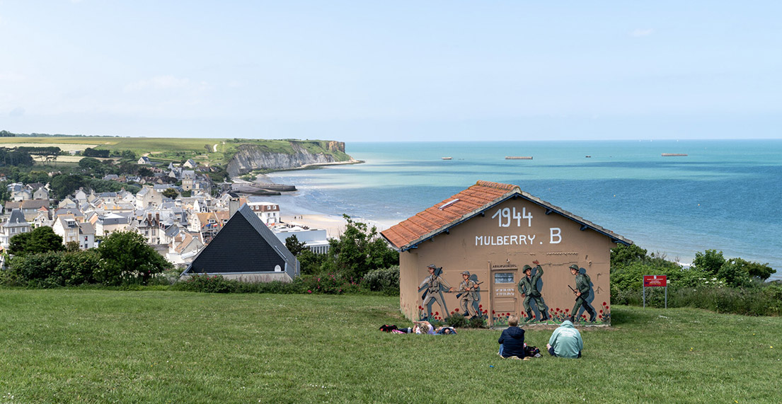 Des personnes assise devant un panorama de falaises devant la mer