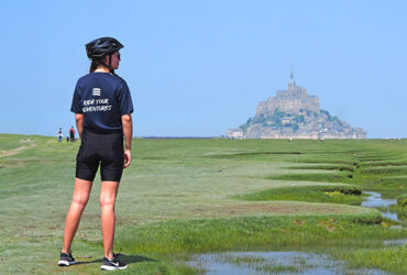 Une cycliste regarde le Mont Saint Michel vu des prés salés