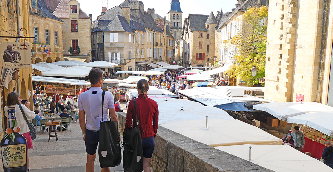 Un couple de cycliste se dirige vers une place de marché