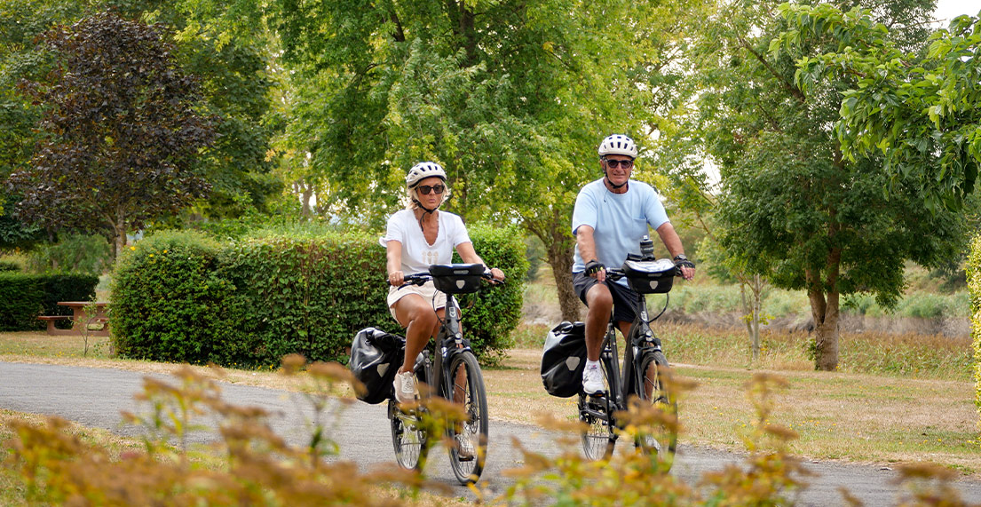 Un couple de cyclistes roule sur une petite route bucolique entouree de verdure