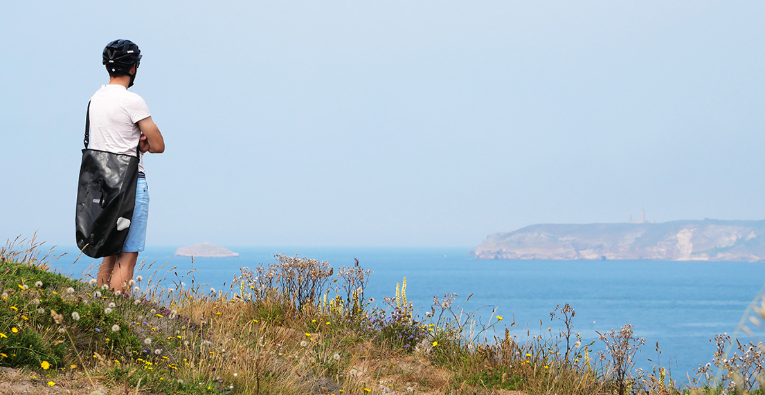 Un cycliste observe la côte bretonne du haut d'une falaise