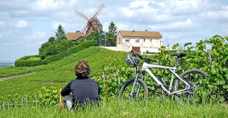 Un cycliste en pause devant un moulin à vent