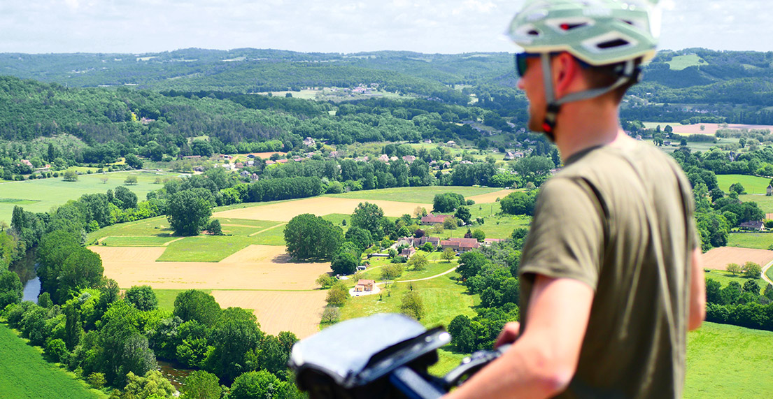 Un cycliste admire la vue panoramique sur la vallée de la Dordogne