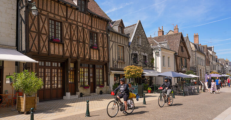 Un couple de cyclistes dans les rues d'Amboise et ses maisons à pant de bois