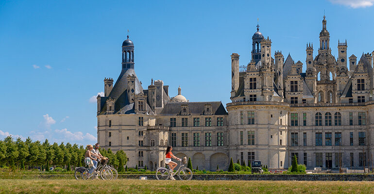 Une famille de cycliste roule devant le château de Chambord