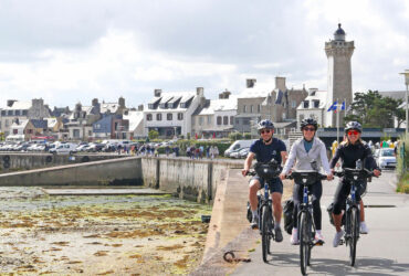 Un groupe de trois ct=cyclistes roule le long du port de Roscoff