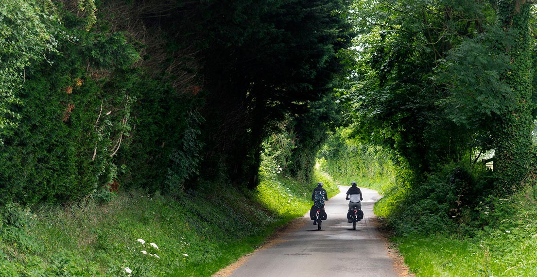 Une famille de cycliste roule sur un chemin de halage entouré de verdure