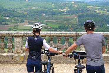 Deux cyclistes marchant à côté de leur vélo face à une vue sur la campagne