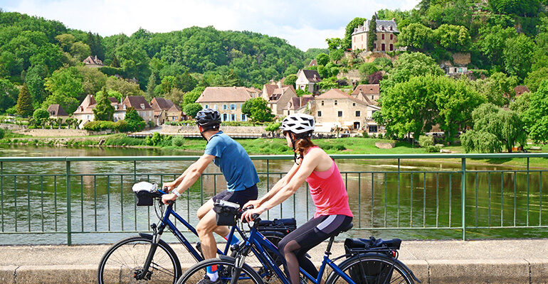 Deux cyclistes sur un pont avec vue sur une citée médiévale