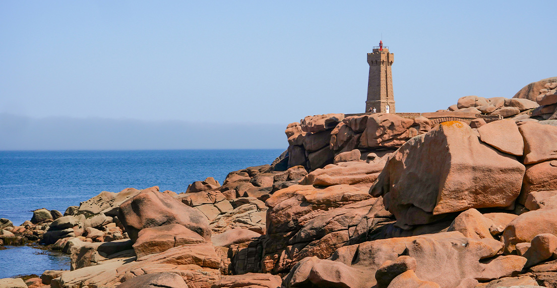 Le phare rose de Ploumanach entoure de rochers et d une mer bleu