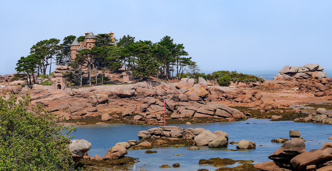 Un chateau de pierres rose se dresse sur un ilot de rochers roses