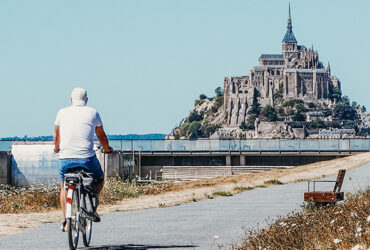 Un cycliste se dirige vers le Mont-Saint-Michel via la piste cyclable