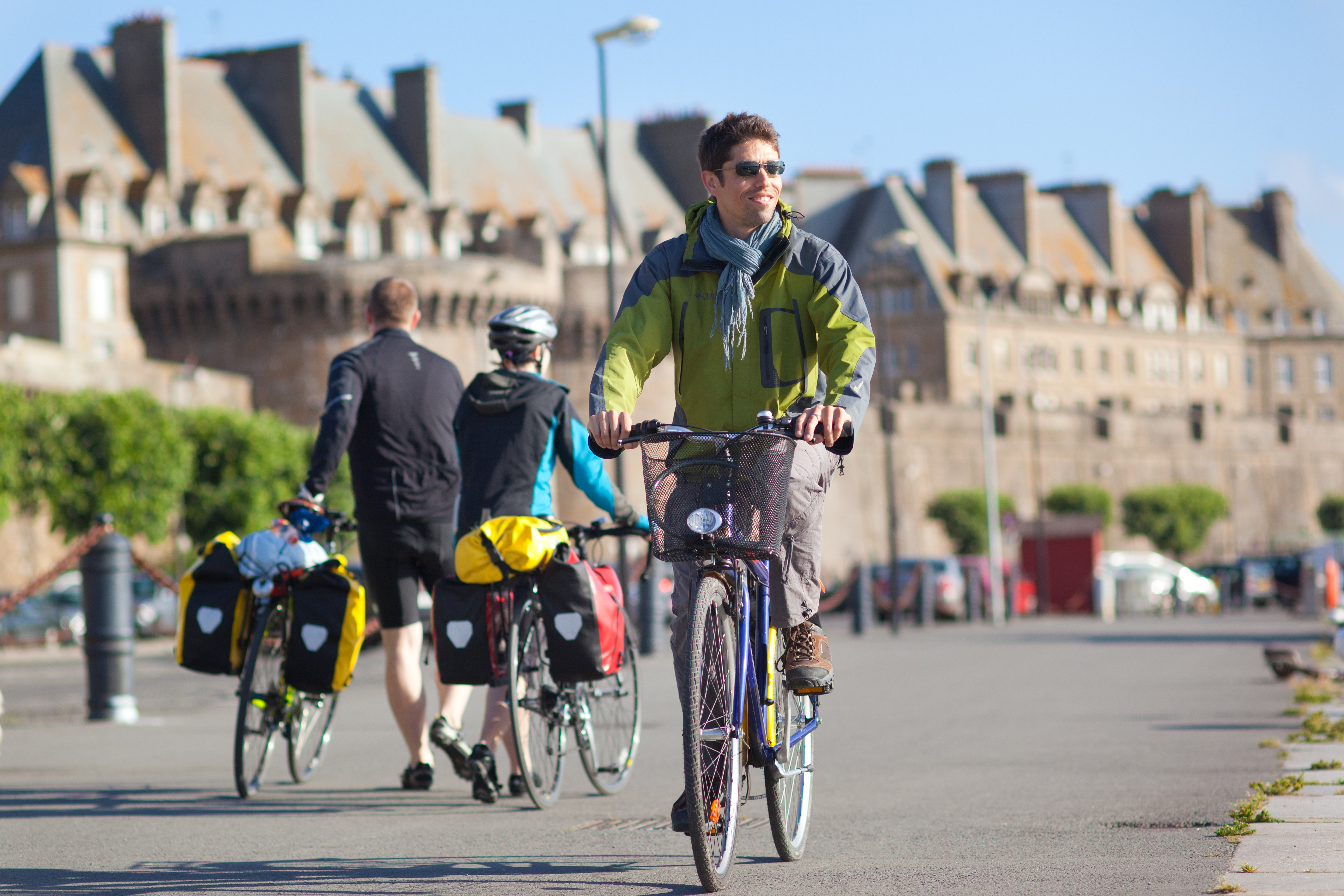 Cycliste à vélo croisant 2 cyclistes à pied devant les remparts de Saint Malo
