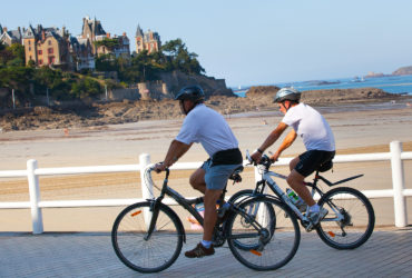 2 cyclistes sur une promenade devant la la plage