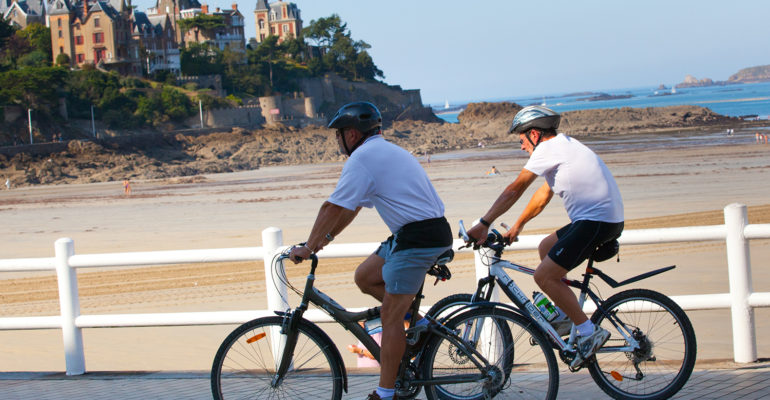 2 cyclistes sur une promenade devant la la plage