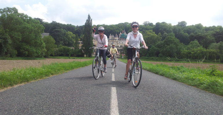 Cyclistes avec chateau en arrière-plan sur une route de la Loire à vélo Val de Loire : Patrimoine mondial