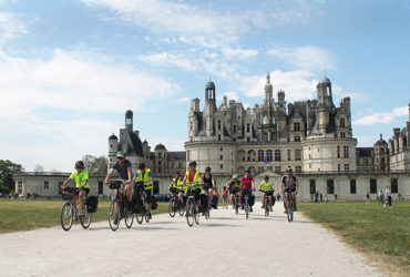 groupe de cyclistes en selle devant le château de chambord