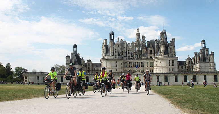 groupe de cyclistes en selle devant le château de chambord