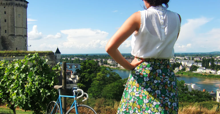 Femme tenue et vélo vintage contemplant le château de Saumur et la Loire