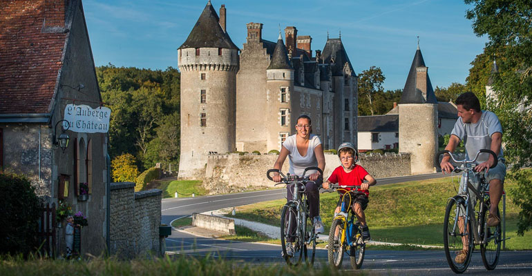 Famille à vélo devant une auberge et un château Loire à vélo