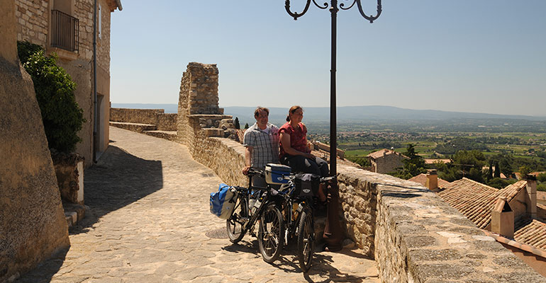 Couple de cyclistes devant panorama de la campagne provençale, halte vacances à vélo en Provence