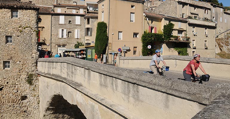 2 cyclistes traversant le pont de Vaison la Romaine, étape vacances à vélo en Provence