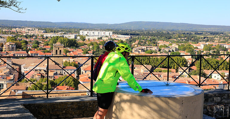 Un couple de cycliste regarde un plan avec une vue panoramique sur un village de Provence