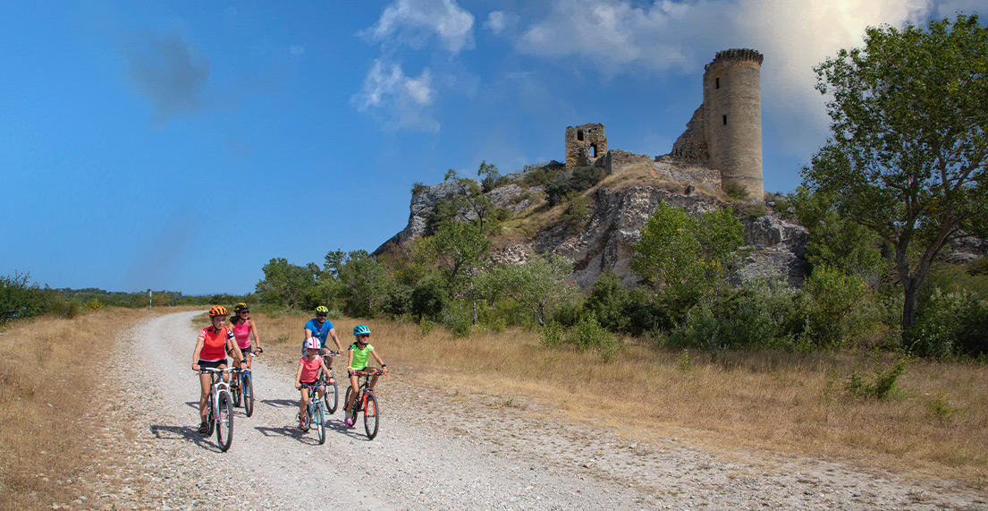 Une famille de cycliste roule entre vignes et roches