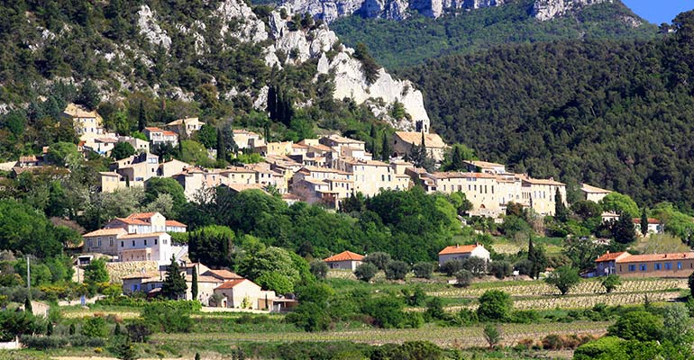 Villange au pied d'une falaise et surplombant des vignes, vacances à vélo en Provence