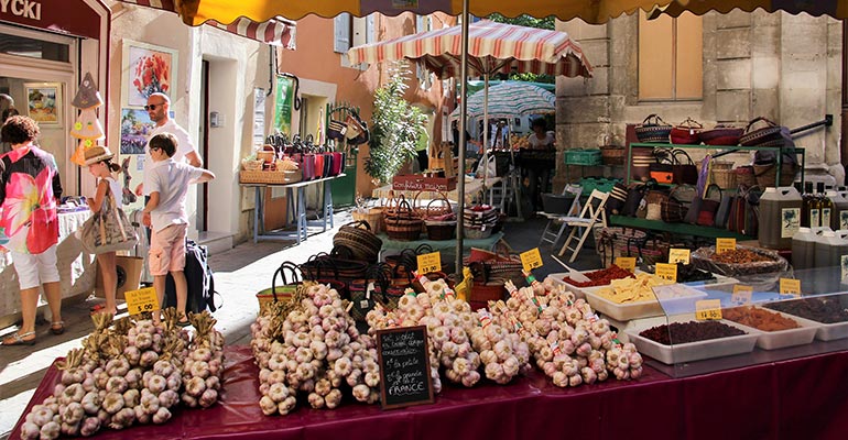 Etals d'ail, d'huile d'olive et d'artisanat sur un marché vacances à vélo en Provence